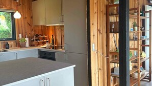 Eine moderne Küche mit Holzvertäfelung, weißen Schränken und einer zentralen Kochinsel.