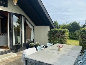 A patio with a table and chairs, a covered seating area, and a garden view. - 4 Star Holiday Home in Karrebaeksminde (Karrebæksminde)