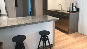 A modern kitchen with granite countertops, stainless steel appliances, and wooden flooring. - 5 Star Holiday Home in Farso (Farso)