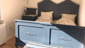 A bedroom with a dark headboard, two bedside tables, a nightstand, and a hanging plant. - 5 Star Holiday Home in Farso (Farso)