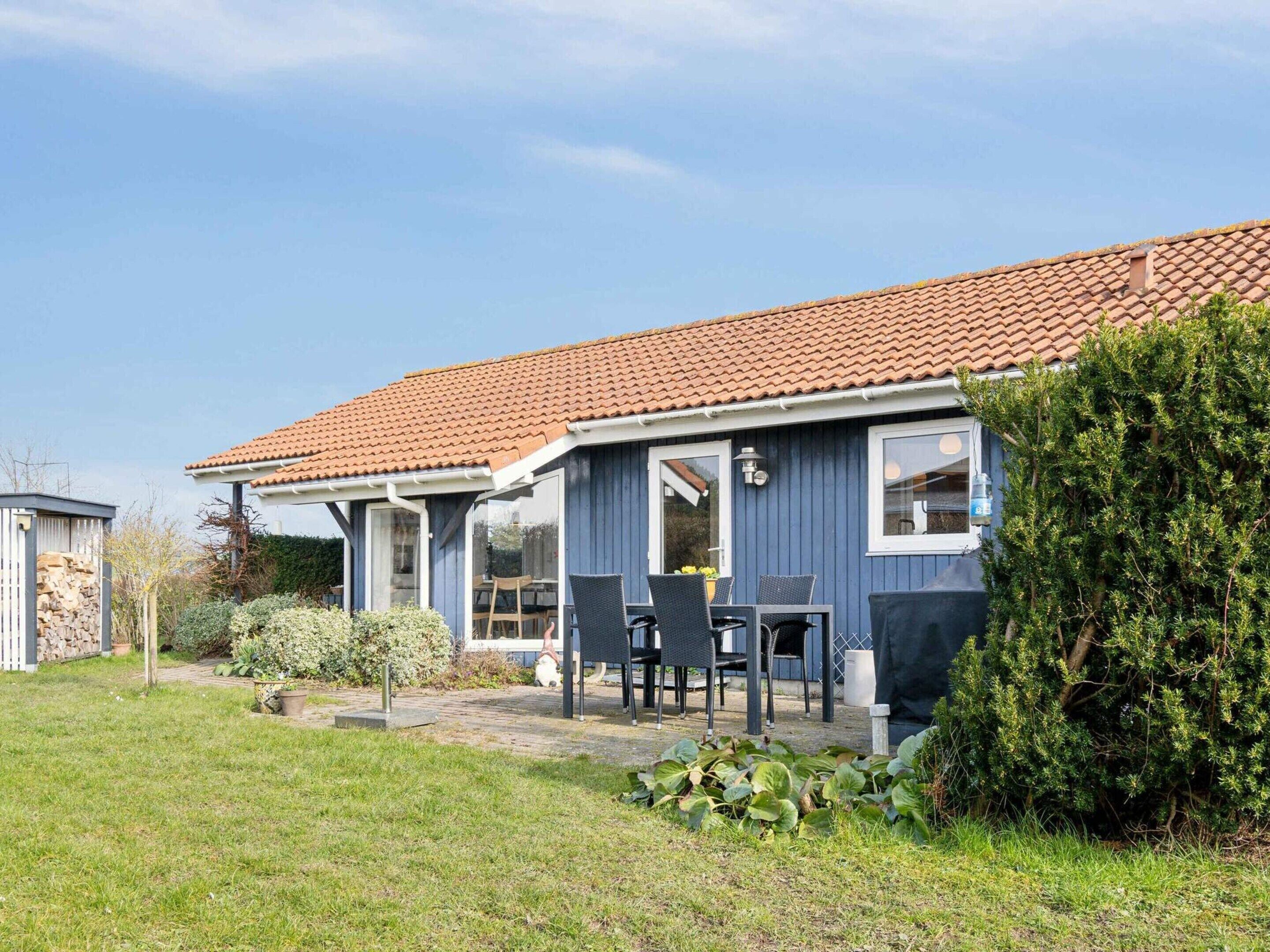 A two-story house with a tiled roof, a covered patio with outdoor furniture, and a well-maintained garden.