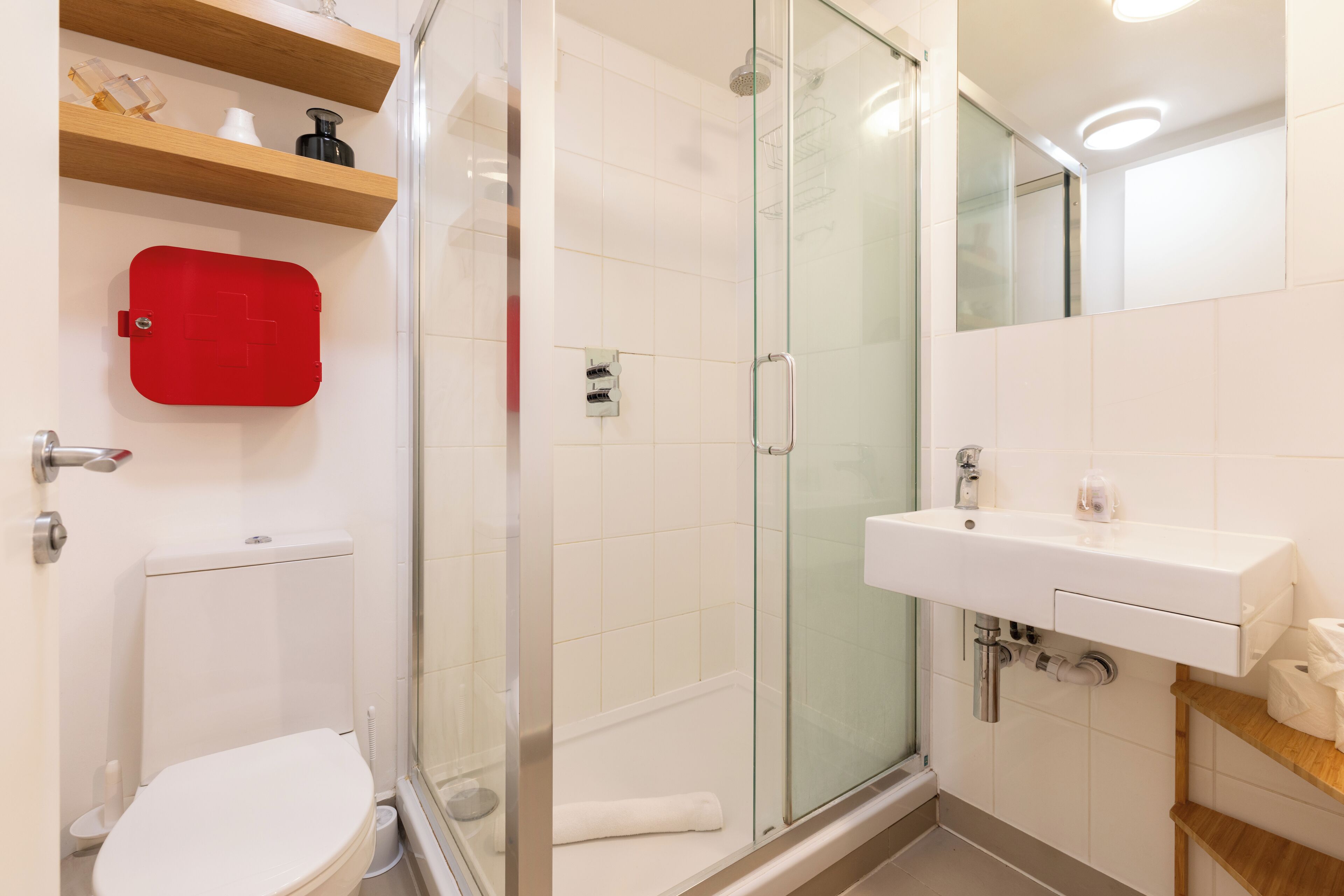 A modern bathroom with a glass shower enclosure, a white toilet, and a white sink with a mirror above it.