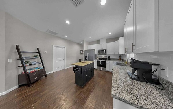 A modern kitchen with white cabinets, a granite countertop, and stainless steel appliances.