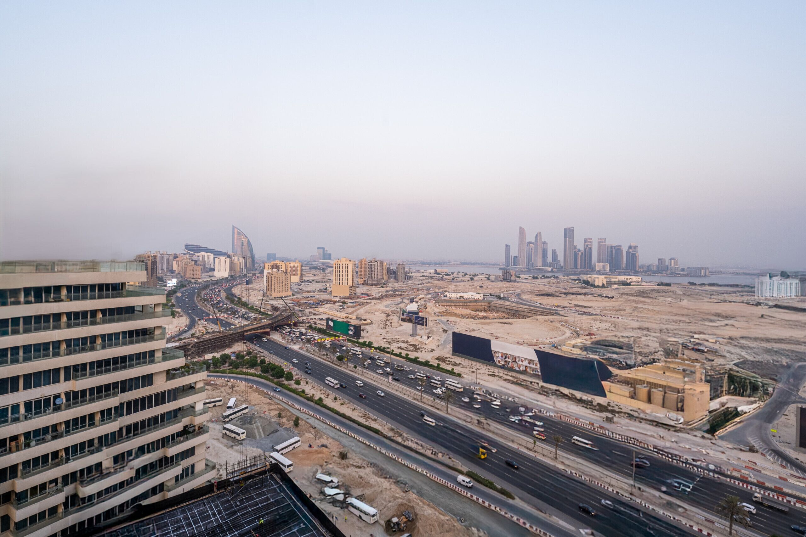 A cityscape with modern buildings, a highway, and construction sites.