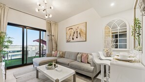 Una sala moderna con un sofá gris, una mesa de centro blanca y un amplio ventanal con vistas a la ciudad.