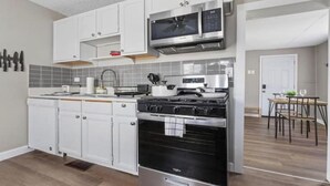 Une cuisine moderne avec des meubles blancs, une cuisinière en acier inoxydable et un four à micro-ondes.