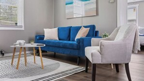 Un salon moderne avec un canapé bleu, un fauteuil blanc et une petite table ronde.