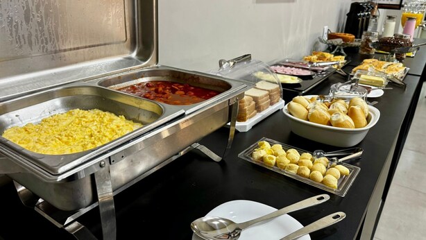 A buffet with various food items including scrambled eggs, baked beans, bread, and pastries.