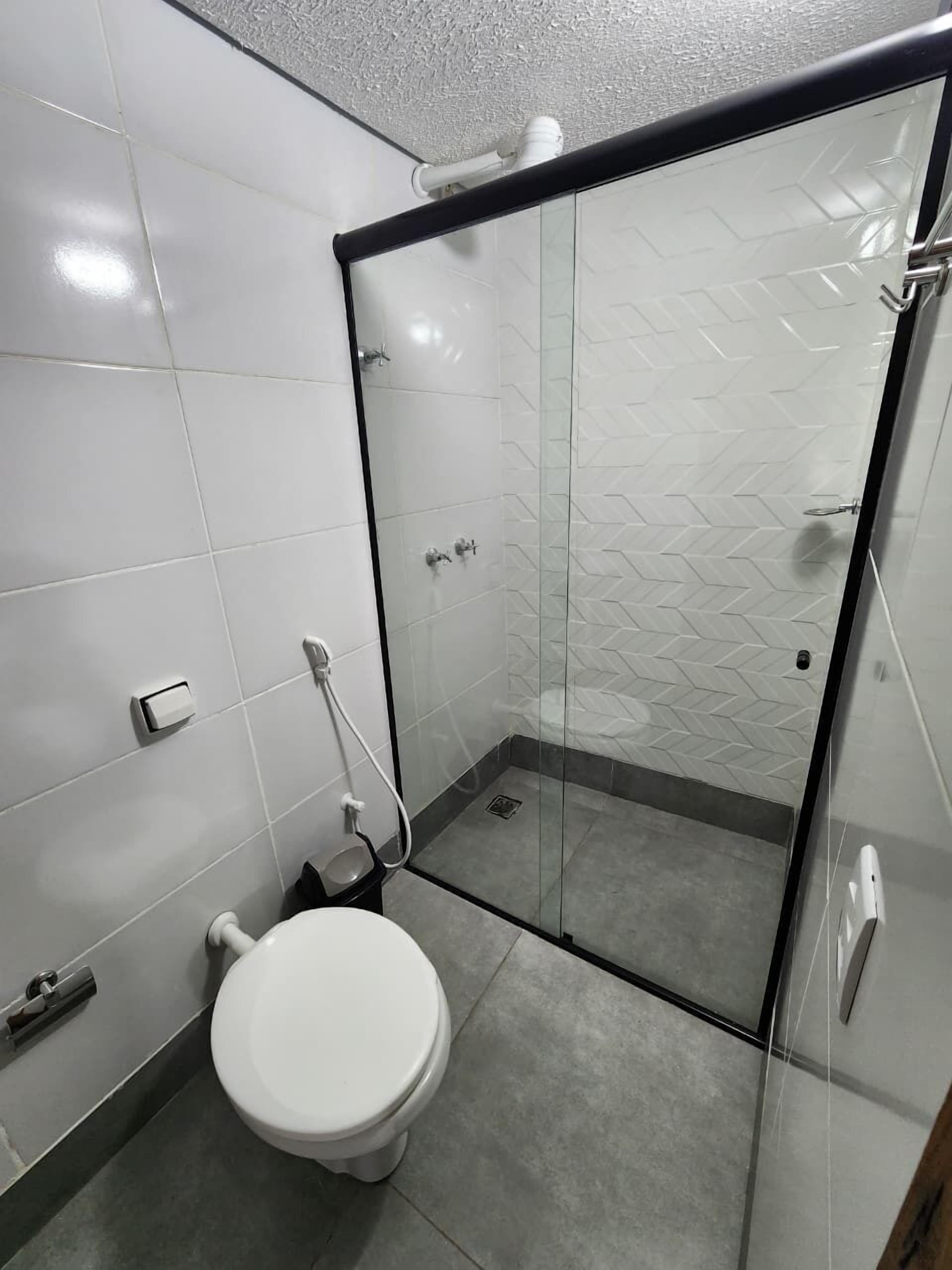 Une salle de bain moderne avec une douche à parois de verre, des toilettes et un lavabo.