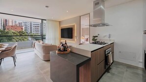 A modern kitchen with a central island, built-in oven, and a large window overlooking a cityscape.