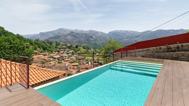 A swimming pool with a view of a village and mountains. - Aurora Holiday Home with Mountain View, Wi-Fi and Air Conditioning (Campo do Gerês)