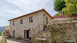 A stone building with a tiled roof, a staircase, and a small outdoor seating area. - Aurora Holiday Home with Mountain View, Wi-Fi and Air Conditioning (Campo do Gerês)