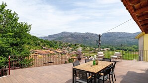 A deck with a table and chairs, overlooking a village and mountains. - Aurora Holiday Home with Mountain View, Wi-Fi and Air Conditioning (Campo do Gerês)