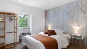 A bedroom with a bed, a wooden shelf unit, a window, and a wall with a nature-themed mural. - Aurora Holiday Home with Mountain View, Wi-Fi and Air Conditioning (Campo do Gerês)