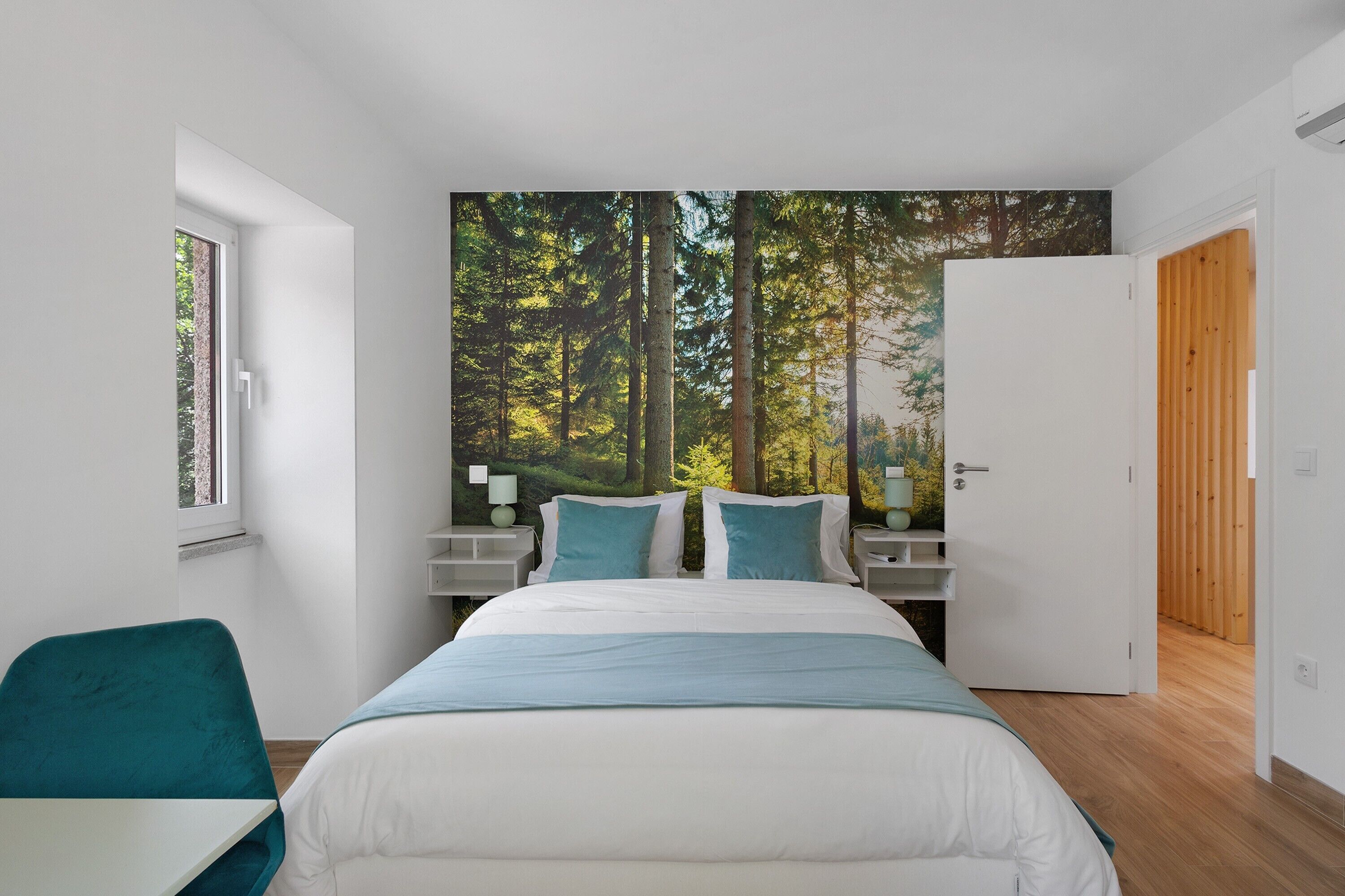 A bedroom with a large bed, two bedside tables, a window, and a door.