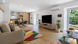 A modern living room with a sofa, TV, and dining area. - Aurora Holiday Home with Mountain View, Wi-Fi and Air Conditioning (Campo do Gerês)