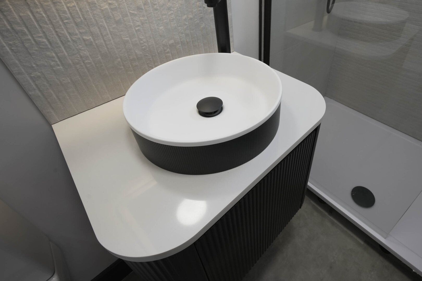 Une salle de bain moderne avec un lavabo blanc et un receveur noir.