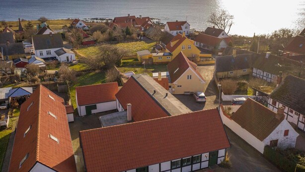 A coastal village with traditional houses, a clear view of the sea, and a small road leading through the center.