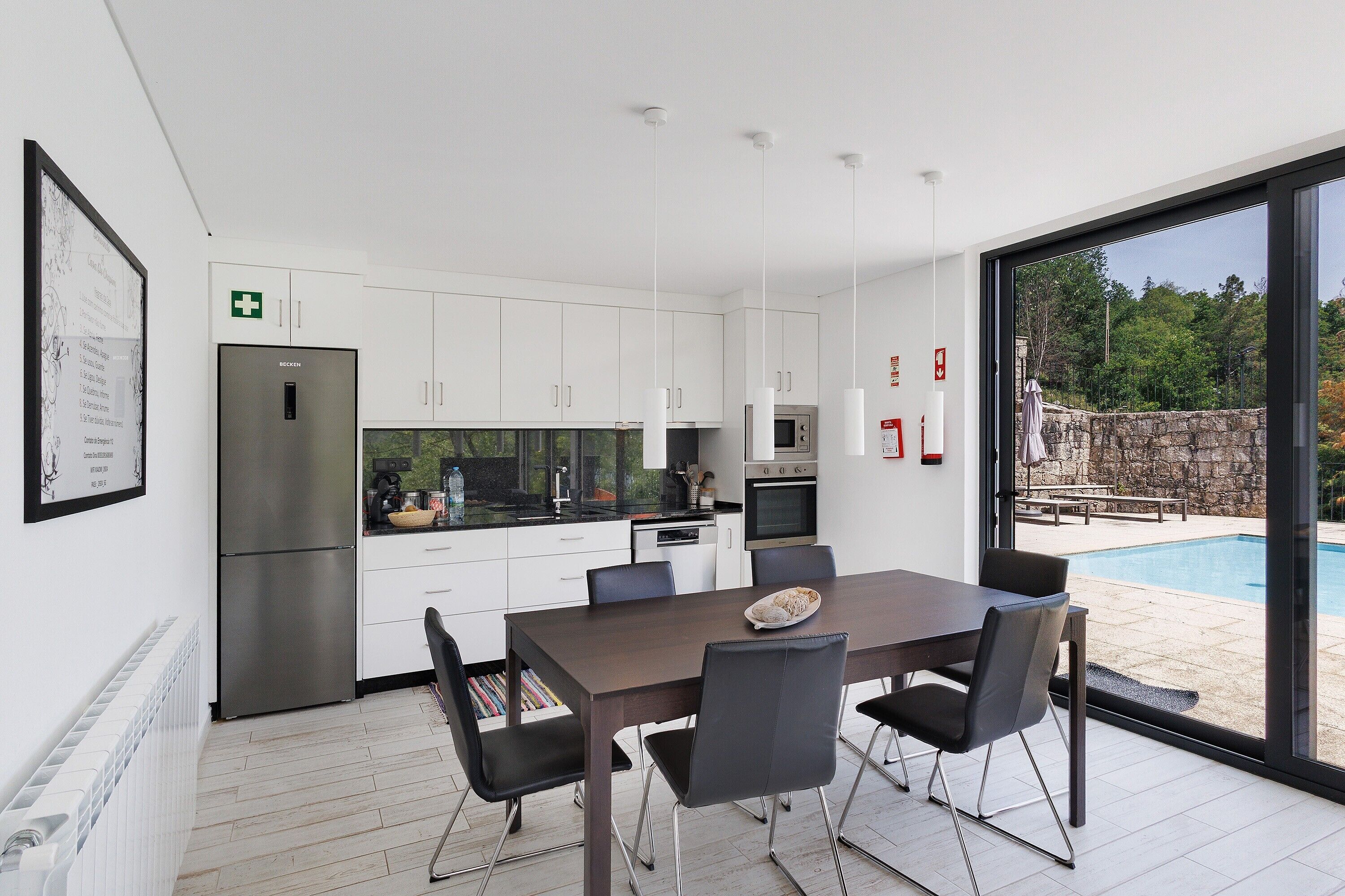 Een moderne keuken met witte kasten, een roestvrijstalen koelkast en een eethoek met een tafel en stoelen.