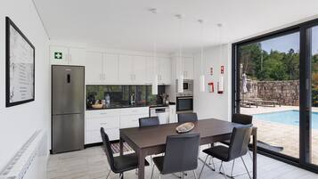 Een moderne keuken met witte kasten, een roestvrijstalen koelkast en een eethoek met een tafel en stoelen.