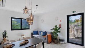 Un interior moderno con zona de comedor, sofá y vistas a través de una puerta de cristal.