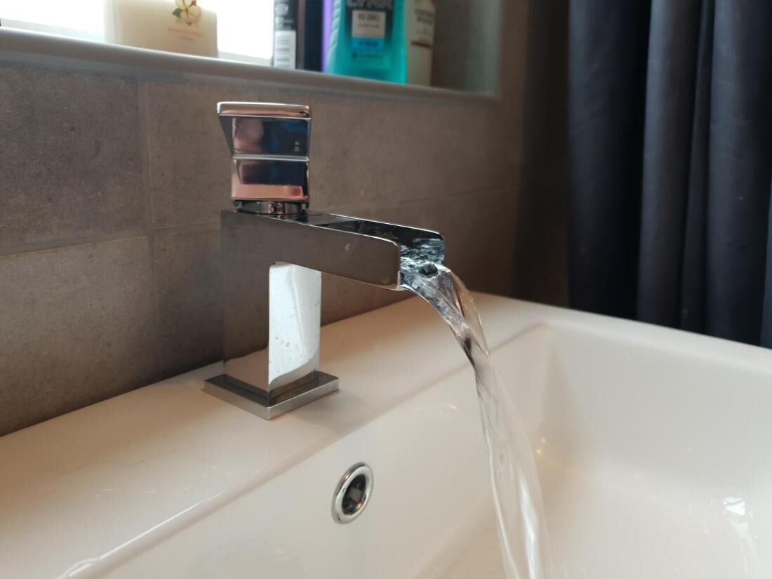 A bathroom sink with a modern faucet and a mirror above it.
