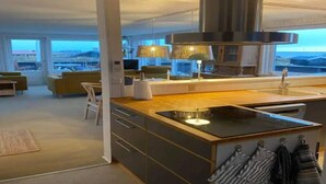 Una cocina moderna con una isla central, estufa integrada y un amplio ventanal con vistas a un paisaje pintoresco.