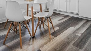 A dining area with a round table and four white chairs with wooden legs. The floor has a herringbone pattern with dark and light wood tones. - Tremont · Group Suite · Prking · Mins to DT · Wifi (Cleveland)