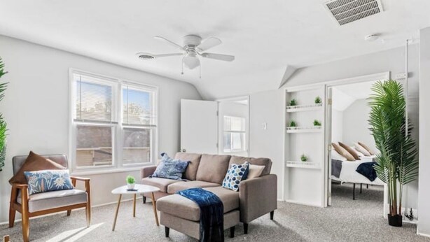 A modern living room with a sofa, armchair, and coffee table, large windows, and a ceiling fan. - Tremont · Group Suite · Prking · Mins to DT · Wifi (Cleveland)