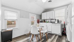 A compact kitchen with white cabinetry, a dining table with chairs, and a ceiling fan. - Tremont · Group Suite · Prking · Mins to DT · Wifi (Cleveland)