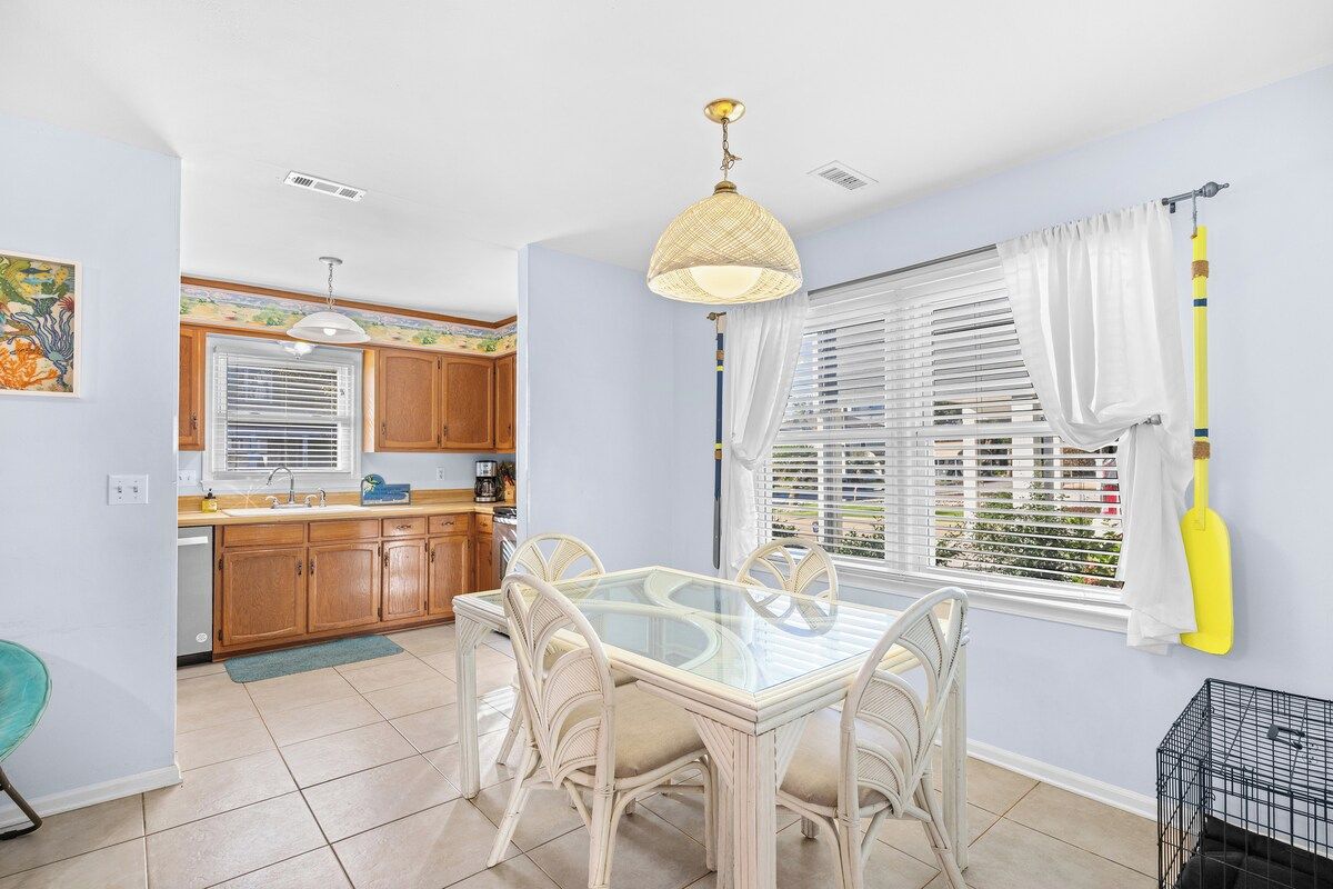 A kitchen with wooden cabinets, a glass dining table, and a hanging light fixture.