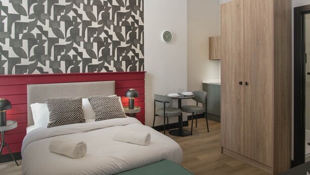 Een moderne hotelkamer met een bed, nachtkastjes, een bureau en een kledingkast.