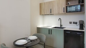 Een kleine keuken met een spoelbak, een koffiezetapparaat en een vaatwasser.