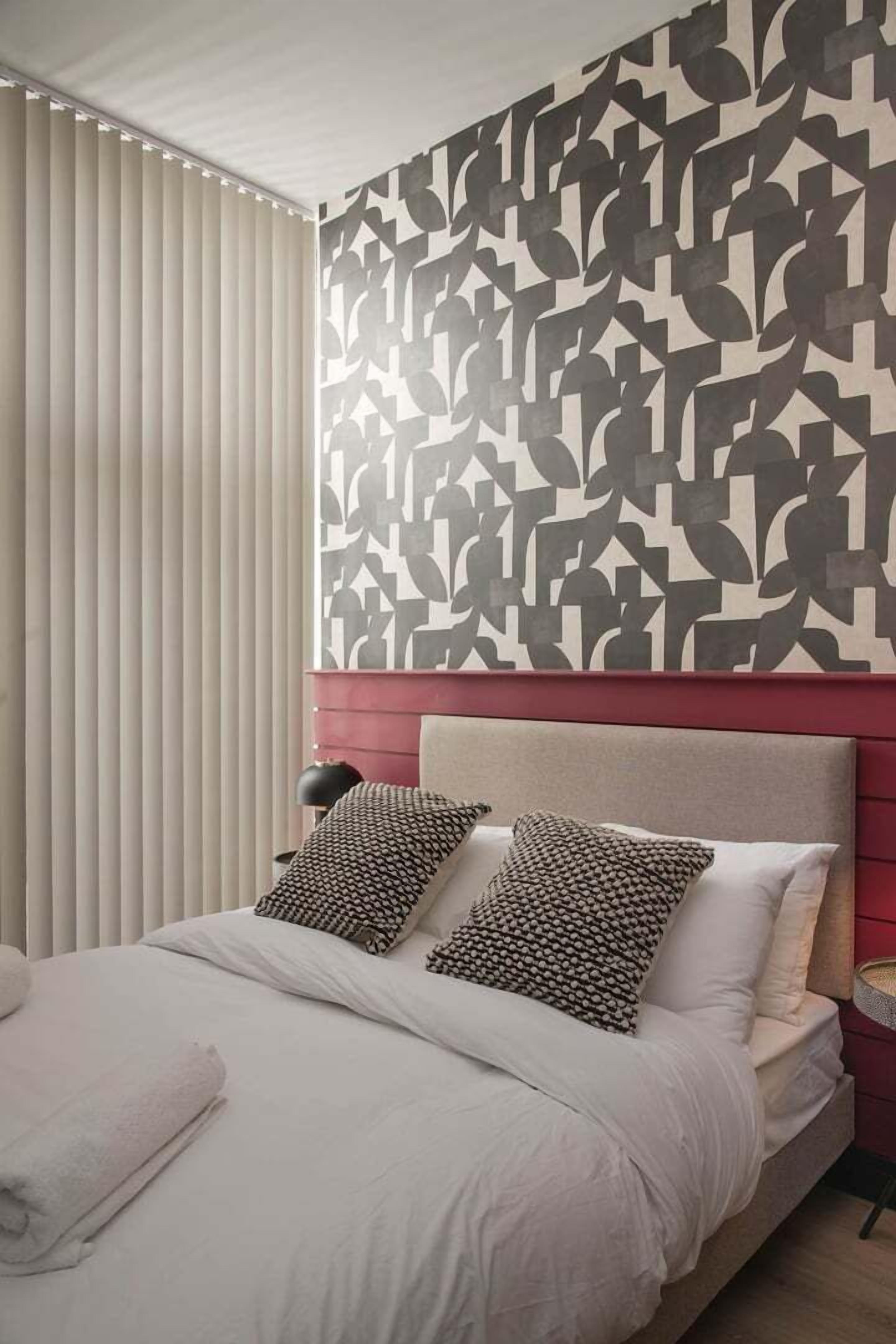 Une chambre moderne avec un mur à motifs, un lit avec des oreillers et une table de chevet.