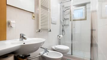 Un bagno con lavabo, bidet, WC e box doccia in vetro.
