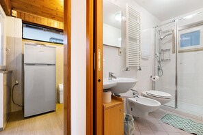 Une petite salle de bain comprenant des toilettes, un bidet, un lavabo et une douche.