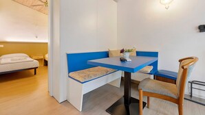 A room with a bed, a blue bench, a wooden chair, a table, and a ceiling fan. - Apartment 'Bungalow Pit Stop' with Lake View, Wi-Fi and Air Conditioning (Brenzone sul Garda)