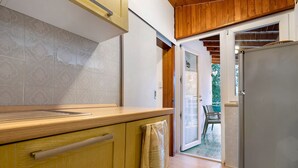 A kitchen with wooden cabinets, a stainless steel refrigerator, and a sliding glass door leading to an outdoor area. - Apartment 'Bungalow Pit Stop' with Lake View, Wi-Fi and Air Conditioning (Brenzone sul Garda)