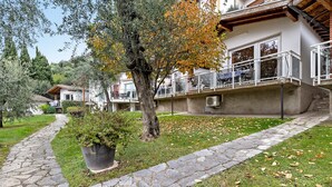 A stone pathway leading to a building with a balcony, surrounded by trees and grass. - Apartment 'Bungalow Pit Stop' with Lake View, Wi-Fi and Air Conditioning (Brenzone sul Garda)