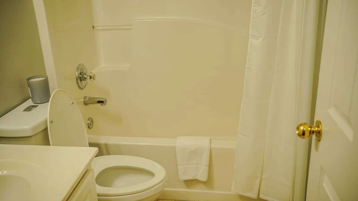 Un baño con inodoro, lavabo, bañera y cortina de ducha.