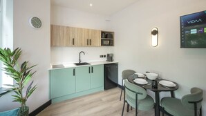 Une cuisine moderne avec des meubles de couleur bois clair, un évier et un coin repas comprenant une table et des chaises.