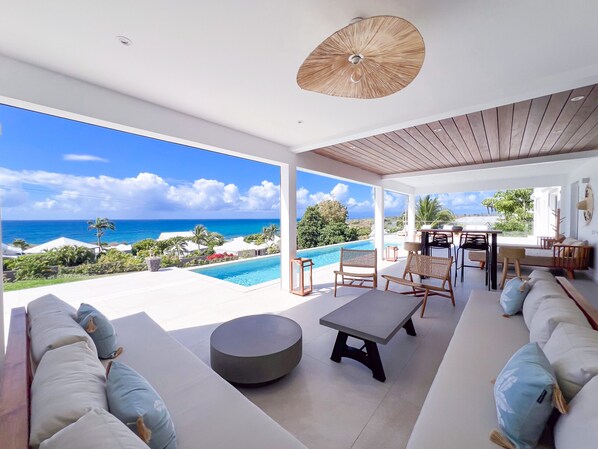 Un salon moderne avec piscine, espace salon extérieur et vue sur l’océan.