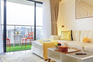 A modern hotel room with a balcony, a sofa, a coffee table, and a view of the city.