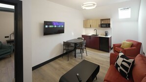 Ein gemütlicher, kompakter Wohnbereich mit Essplatz, Küchenzeile und Wandfernseher.