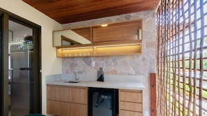Una cocina compacta con protector mural de piedra, armarios de madera y microondas integrado.