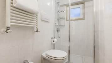Un bagno con un WC bianco, una cabina doccia in vetro e un porta asciugamani.