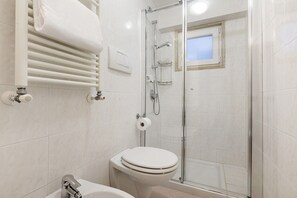 A bathroom with a white toilet, a glass shower enclosure, and a towel rack.