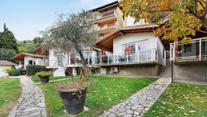 Ein Wohngebäude mit einem Pflasterweg, Blumentöpfen und einem Balkon.