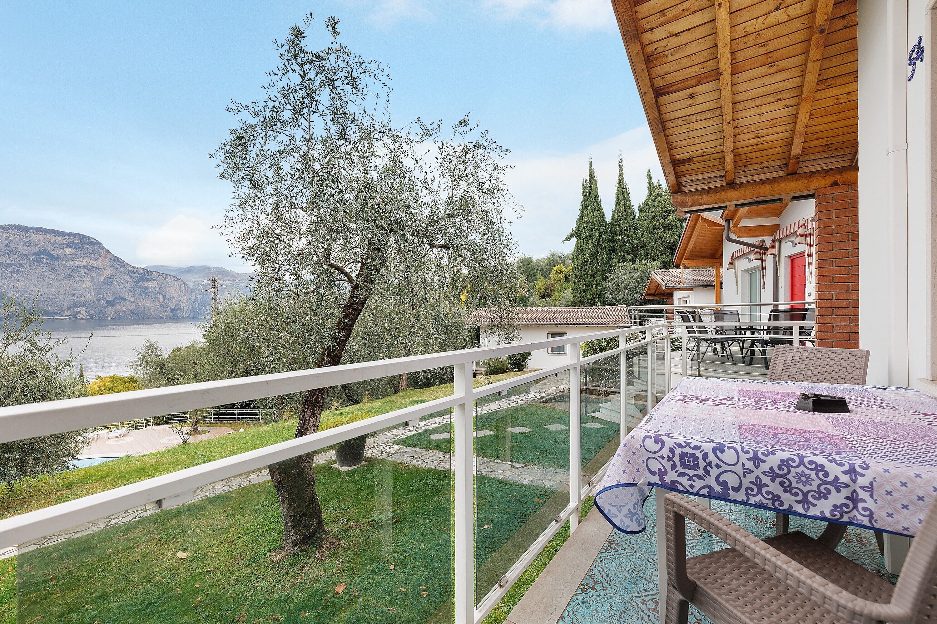 Un balcon donnant sur un lac, une table recouverte d’une nappe et un plafond en bois.