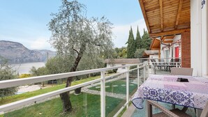 Ein Balkon mit Blick auf einen See, ein Tisch mit Tischdecke und eine Holzbalkendecke.